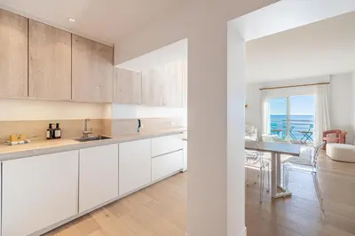 a kitchen with white cabinets and a dining room at 49 CLEM - Superbe appartement 2 chambres 4 pers avec vue mer in Cannes