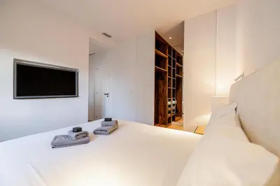 a bedroom with a white bed with a tv on the wall at 49 CLEM - Superbe appartement 2 chambres 4 pers avec vue mer in Cannes