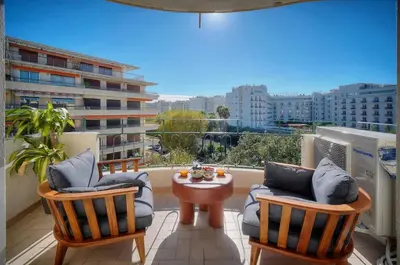 a balcony with two chairs and a table and a window at Seabatical Apartment by the beach, 2Bed and 2Baths in Cannes