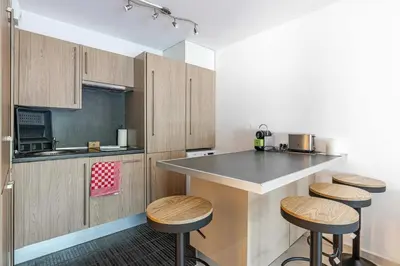 a kitchen with wooden cabinets and a counter with stools at Magnificent apartment with parking - AC-balcony in Cannes