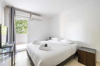 a white bedroom with a large bed and a window at Magnificent apartment with parking - AC-balcony in Cannes