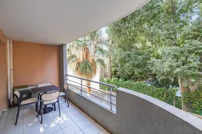 a balcony with a table and chairs and a palm tree at Magnificent apartment with parking - AC-balcony in Cannes