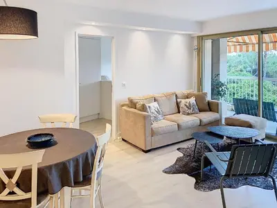 a living room with a couch and a table and chairs at Superbe appartement terrasse vue mer 347L GLEN in Cannes