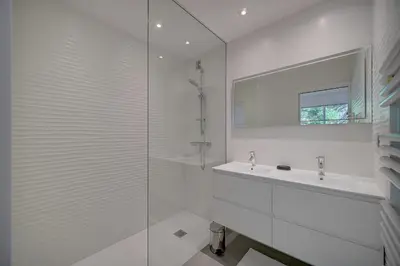 a white bathroom with a sink and a glass shower at REF 1425 - Cannes Center - Apartment for rent in Cannes