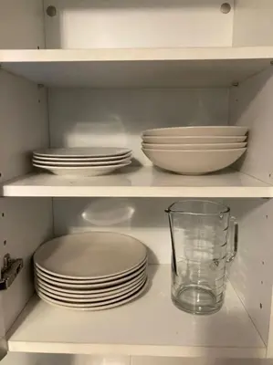 a white cabinet filled with plates and bowls and a glass at Centre-ville de Cannes 100 m mer in Cannes