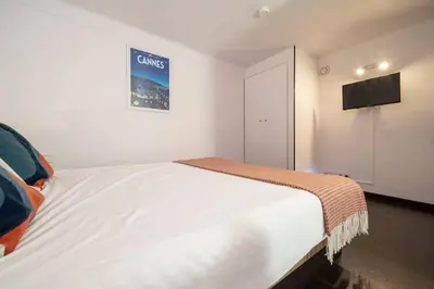 a bedroom with a large white bed with a tv on the wall at Centre-ville de Cannes 100 m mer in Cannes