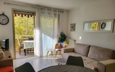 a living room with a couch and a large window at Charmant 2 pièces, traversant, clim, wifi, parking in Cannes