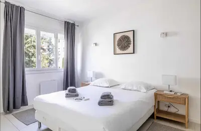 a white bedroom with a white bed and a window at Appartement disign CLUB B in Cannes