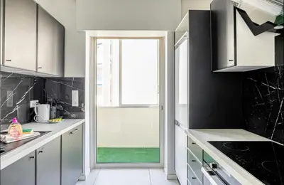 a kitchen with white cabinets and a large window at Appartement disign CLUB B in Cannes