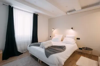 a bedroom with a large white bed with black curtains at Bulle d'Amour - Jacuzzi, 10mn Palais&Plage, Centre in Cannes