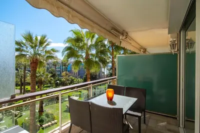 a balcony with a table and chairs and palm trees at REF 30 - Cannes Croisette - Sea and gardens view apartment for rent in Cannes