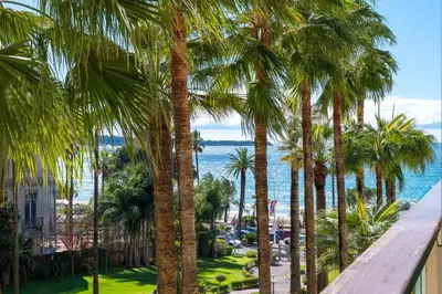 a view of the ocean from a balcony with palm trees at REF 30 - Cannes Croisette - Sea and gardens view apartment for rent in Cannes