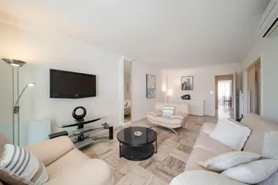 a living room with white furniture and a flat screen tv at REF 30 - Cannes Croisette - Sea and gardens view apartment for rent in Cannes