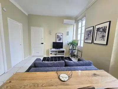 a living room with a blue couch and a tv at Forville Coeur de Cannes in Cannes
