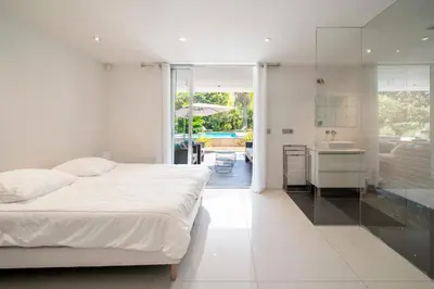 a white bedroom with a bed and a kitchen at REF 1941 - Cannes Center - Villa for rent in Cannes