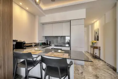a kitchen with a island with chairs and a counter top at Luxury Superbe Studio MIRAMAR Croisette by RIVAEVENT in Cannes