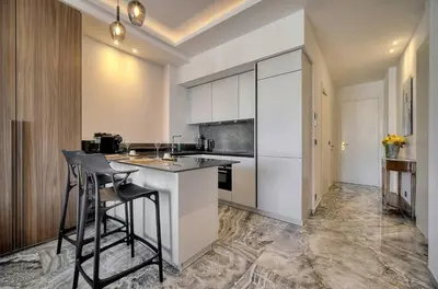a kitchen with white cabinets and a bar with stools at Luxury Superbe Studio MIRAMAR Croisette by RIVAEVENT in Cannes