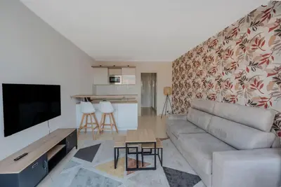a living room with a couch and a tv at Le Grand Hôtel -Centre Croisette in Cannes