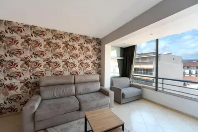 a living room with a couch and a large window at Le Grand Hôtel -Centre Croisette in Cannes