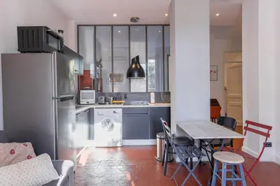 a kitchen with a refrigerator and a table with chairs at L'Atelier - Jardin, 8mn Palais&Plage, spacieux in Cannes
