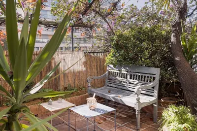 a wooden bench in a garden with a fence at L'Atelier - Jardin, 8mn Palais&Plage, spacieux in Cannes