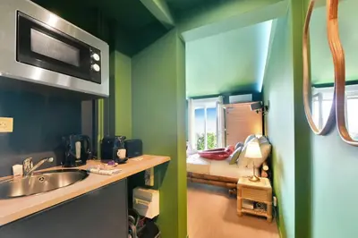 a bathroom with a sink and a room with a bed at The Jungle - Jacuzzi, Sauna & Projector in Cannes