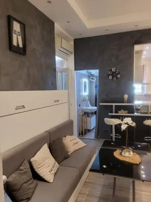 a living room with a couch and a table at Villa Gustave, studio confort avec balcon Centre Cannes in Cannes