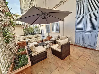 a patio with chairs and an umbrella on a balcony at Beautiful 2 bedroom bourgeois style Antibes 333 in Cannes