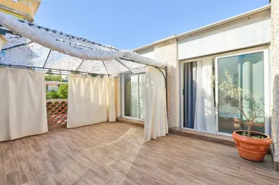 a patio with curtains and a large window at L'Écrin d'Azur – Villa, Cinéma & Plage à 50m in Cannes