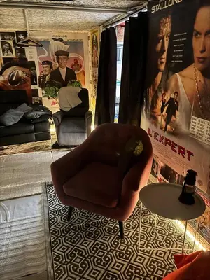 a living room with a chair and a table and posters at L'Écrin d'Azur – Villa, Cinéma & Plage à 50m in Cannes