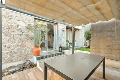 a patio with a table and a stone wall at L'Écrin d'Azur – Villa, Cinéma & Plage à 50m in Cannes
