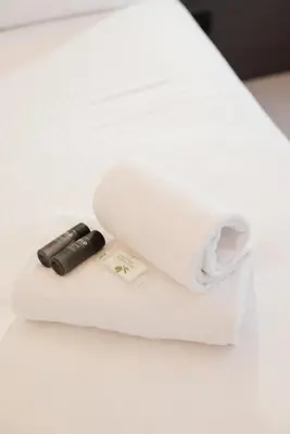 a roll of white towels with a syringe on a bed at Moderne et Chic T3, à deux pas de la Croisette in Cannes