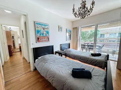 a bedroom with two beds and a chandelier at 85m2 Grandes Terrasses - 2 chambres in Cannes