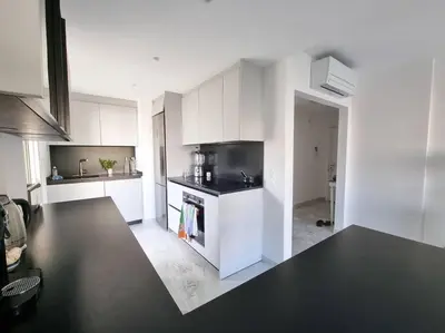 a kitchen with white cabinets and a black counter top at 85m2 Grandes Terrasses - 2 chambres in Cannes