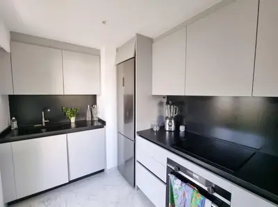 a kitchen with white cabinets and black counter tops at 85m2 Grandes Terrasses - 2 chambres in Cannes
