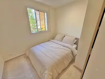a small bedroom with a bed with a window at LE TRAVOLTA avec merveilleuse terrasse, chic et lumineux à deux pas du centre-ville in Cannes