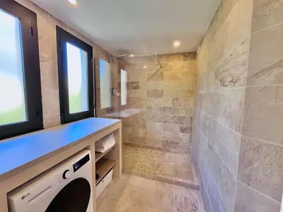 a bathroom with a shower and a sink and a washing machine at LE TRAVOLTA avec merveilleuse terrasse, chic et lumineux à deux pas du centre-ville in Cannes