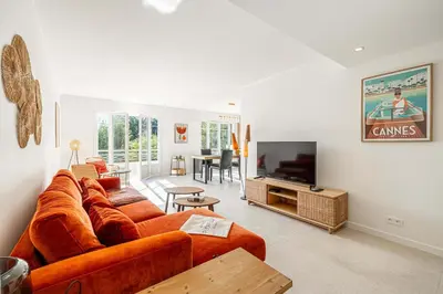 a living room with a couch and a television at LE GRAND BOIS élégant et chaleureux avec balcon, au calme et à deux pas du centre-ville in Cannes