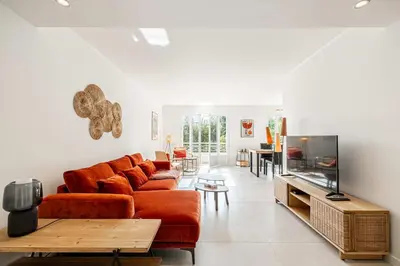 a living room with a couch and a flat screen tv at LE GRAND BOIS élégant et chaleureux avec balcon, au calme et à deux pas du centre-ville in Cannes