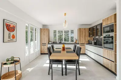 a kitchen with a wooden table and chairs at LE GRAND BOIS élégant et chaleureux avec balcon, au calme et à deux pas du centre-ville in Cannes
