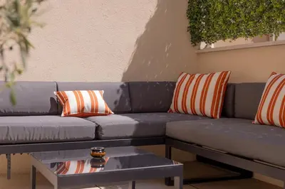 a blue couch with orange and white pillows and a table at Extraordinaire avec terrasse in Cannes