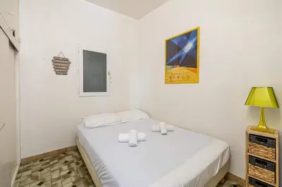 a small bedroom with a bed and a lamp at LE FORVILLE lumineux en plein centre, à deux pas du Palais, Croisette et plages in Cannes