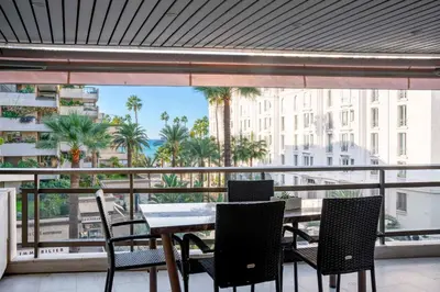 a table and chairs on a balcony with a view of a city at REF 1924 - Cannes Croisette - Sea view apartment for rent in Cannes