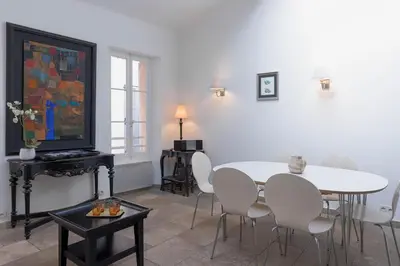 a dining room with a white table and white chairs at Maison Julia- Triplex avec rooftop terrasse vue sur mer et cathédrale, 10 mins à pieds du palais et plages in Cannes