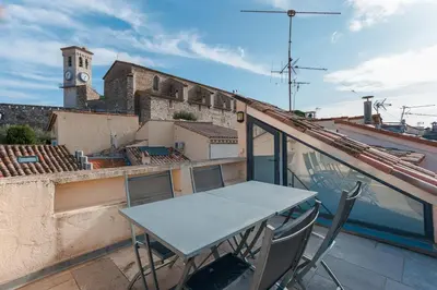 a table and chairs on a balcony with a clock tower at Maison Julia- Triplex avec rooftop terrasse vue sur mer et cathédrale, 10 mins à pieds du palais et plages in Cannes