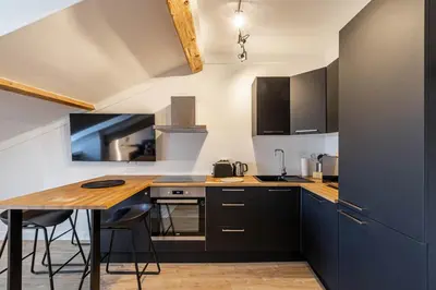 a kitchen with black cabinets and a wooden table at 5 CARNOT - Beautiful apartment, 4 people, 150m from Palais des Festivals in Cannes