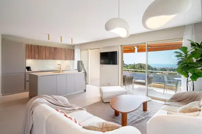 a living room with white furniture and a kitchen at REF 1965 - Le Cannet - Sea view apartment for rent in Le Cannet