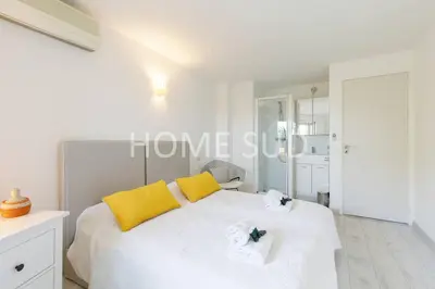 a bedroom with a large white bed with yellow pillows at Votre maison de vacances dans un écrin de verdure - Cannes in Cannes