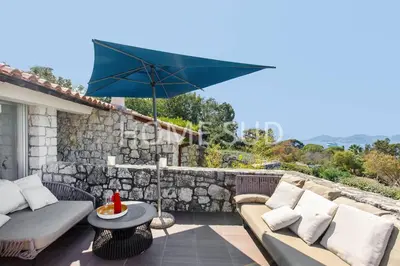 a patio with a couch and an umbrella at Votre maison de vacances dans un écrin de verdure - Cannes in Cannes