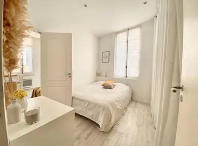 a white bedroom with a bed and a window at Joli appartement au calme à 10 min à pied des Marches et des plages in Cannes